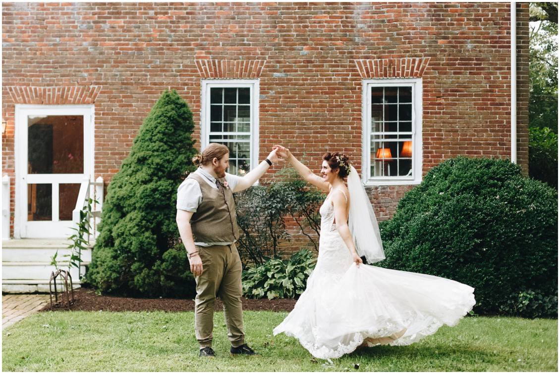Groom twirling bride in front of brick backdrop at Whitebarn at Middlespring. |Eastern Shore Wedding|