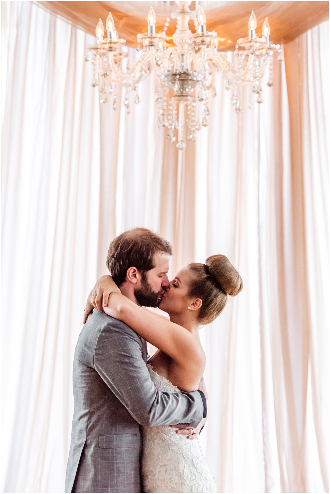 Large crystal chandelier over bride and groom, kissing. | My Eastern Shore Wedding | 