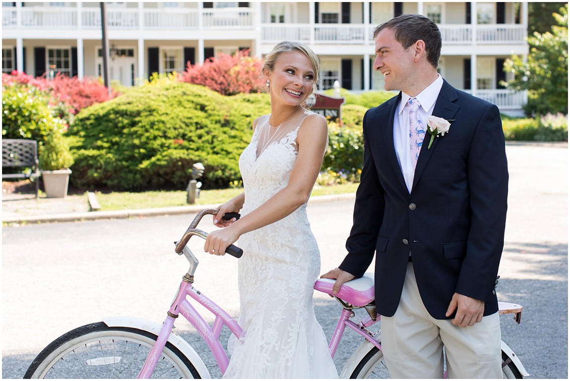 Bride and groom standing by pink and white bicycle together. | My Eastern Shore Wedding | 