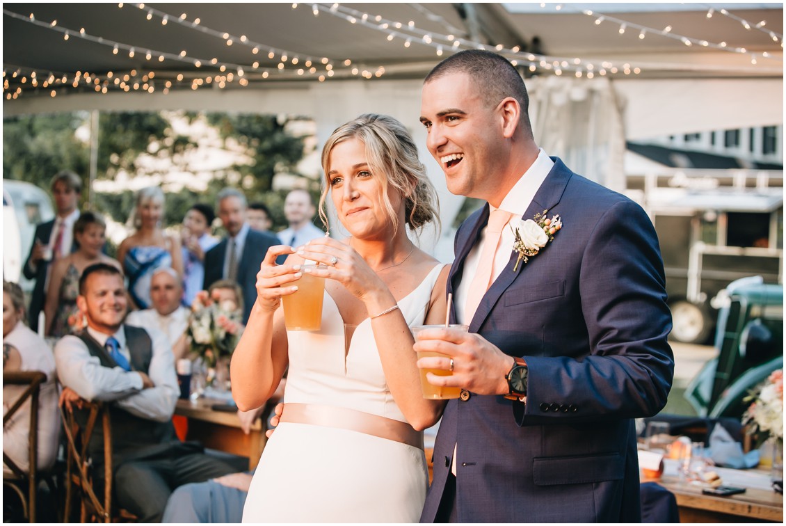 Bride and groom at reception, holding drinks, listening to speeches. | My Eastern Shore Wedding | 