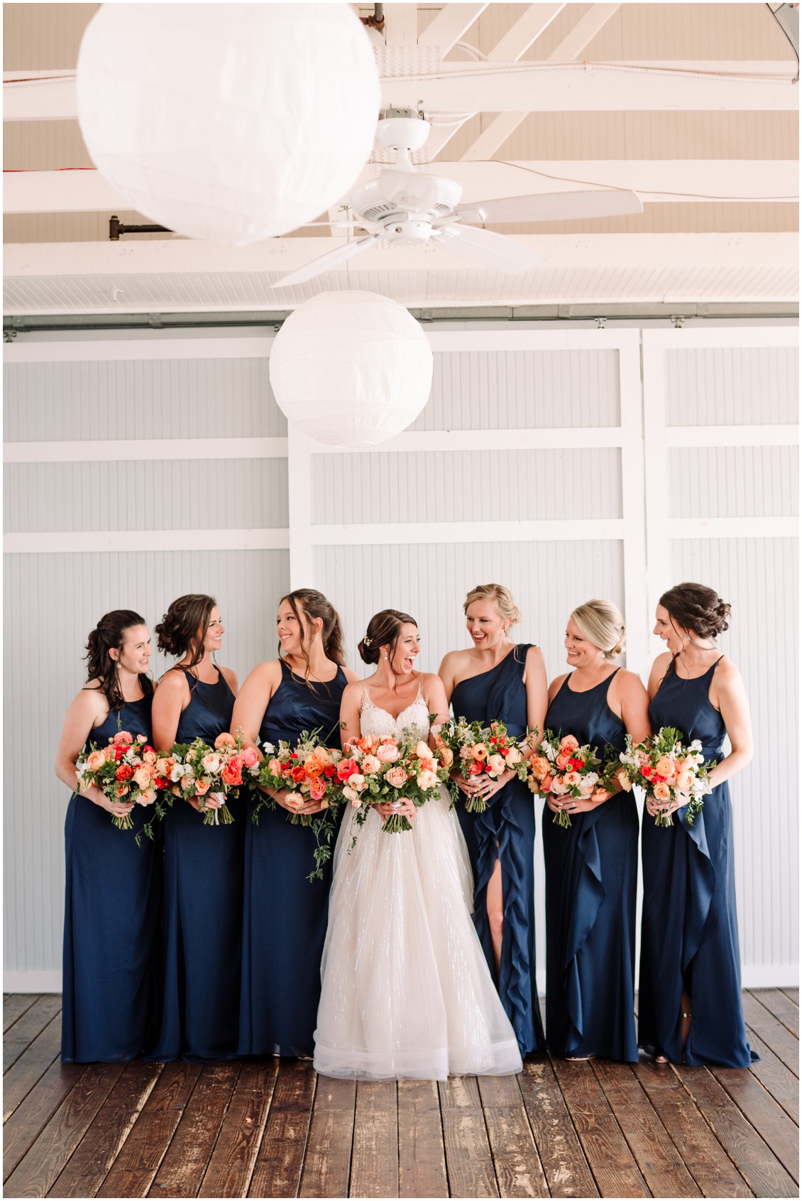 Bride and bridesmaids in dark blue dresses with bright bouquets at bayside celebration | My Eastern Shore Wedding | Chesapeake Bay Beach Club