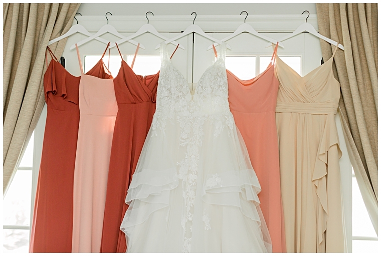 Bridesmaid dresses hang in the window with the bridal gown | Cassidy MR Photography