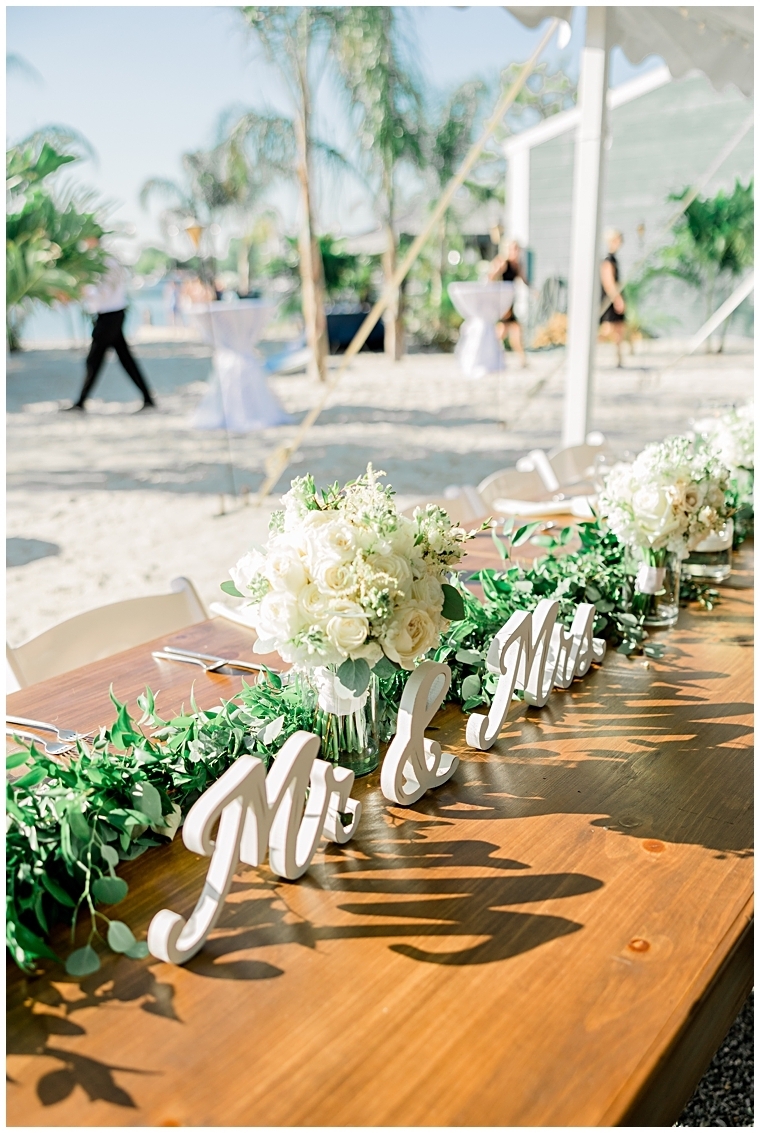 The head table is decorated with greenery along with the bridal party bouquets | Chesapeake Blooms