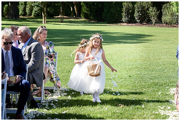 Flower girls decorate the aisle with white petals for the bride