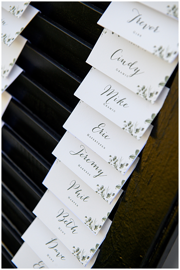 Escort cards on beautiful display with hints of greenery to match the ceremony details
