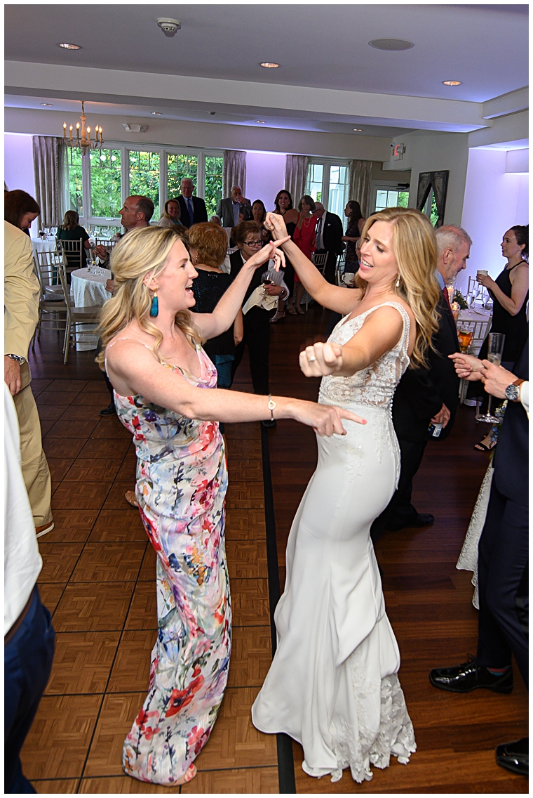 The bride dances with a friend on the dance floor inside at The Oaks Waterfront Inn