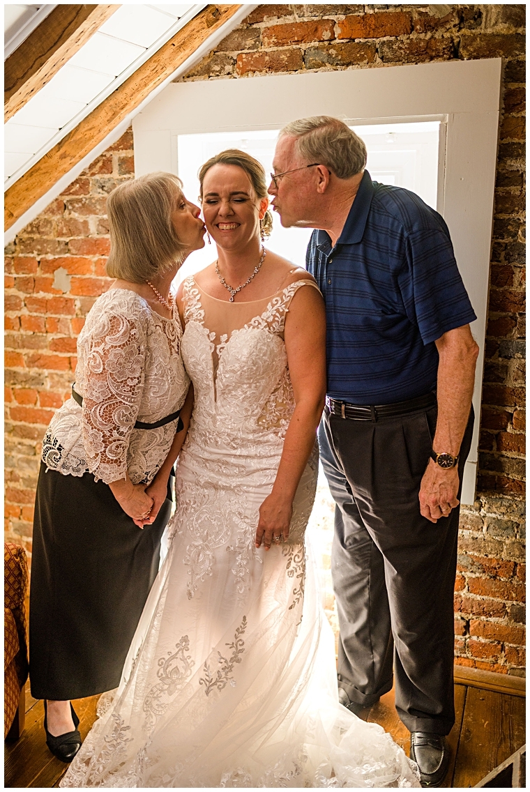 Mother and father of the bride post for a photo with their daughter on her big day.