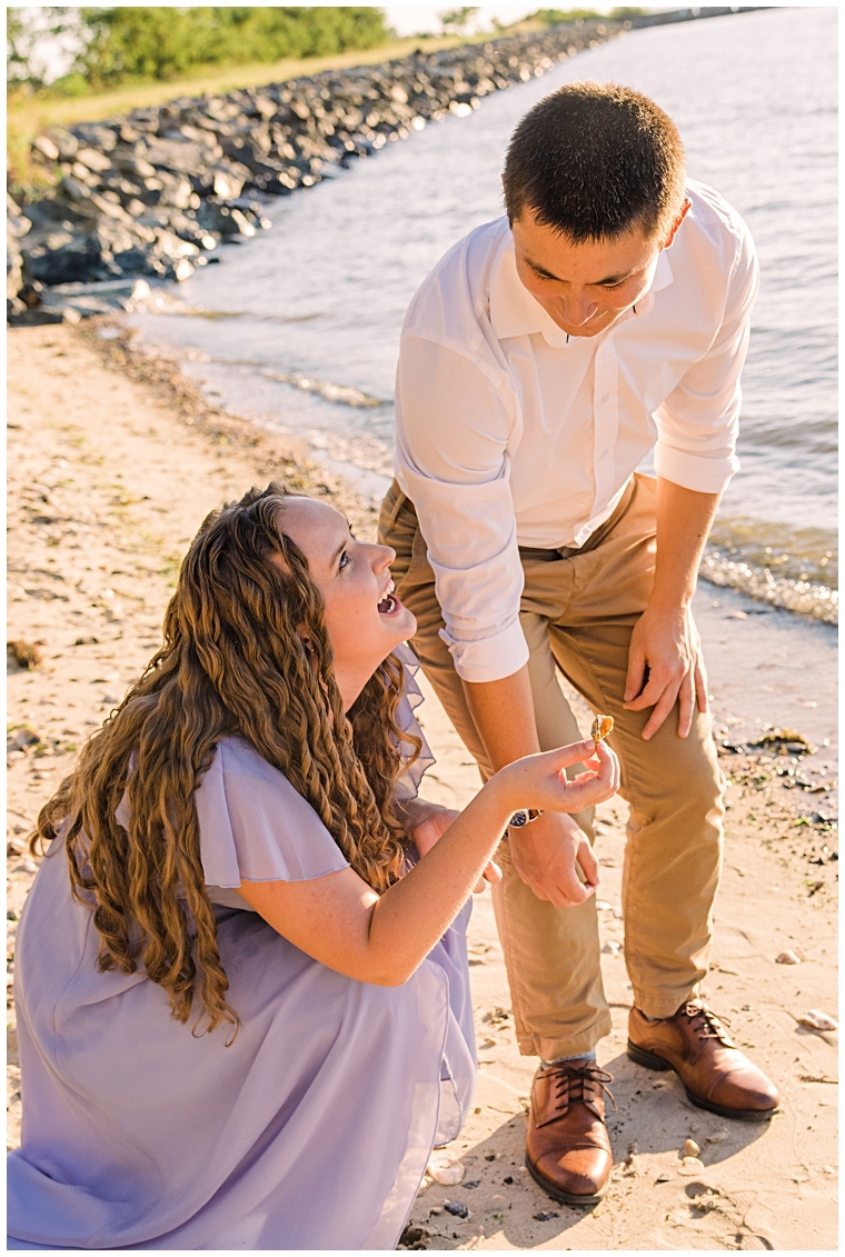 Playing in nature, the betrothed couple inspects a shell that they found on the shore of the Miles River | My Eastern Shore Wedding | Laura's Focus Photography