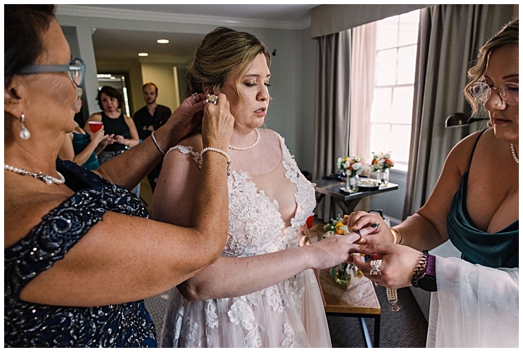 The mother of the bride helps her daughter with her jewelry before the ceremony