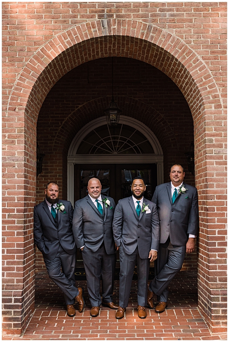 The groom and his groomsmen pose for a portrait in the archways at The Tidewater Inn
