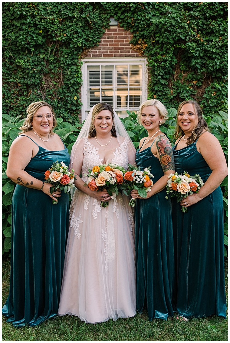 The bride is surrounded by her bridesmaids in their emerald green gowns