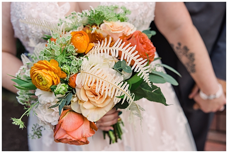 A bridal bouquet including marigold and sunset orange florals by Sweetbay Designs