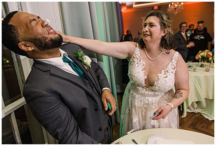 The bride and groom share a playful tasting of their wedding cake