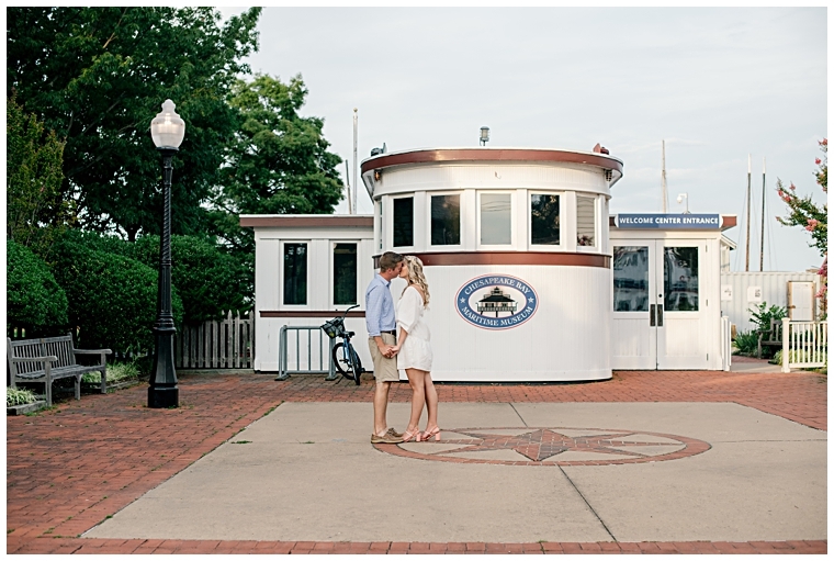 Fiancees embrace in a sweet kiss in front of the gate to The Chesapeake Bay Maritime Museum