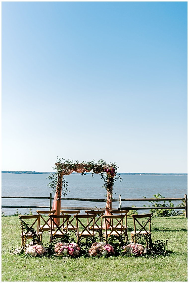 A waterfront ceremony site detailed with pink and white florals at Great Oak Manor