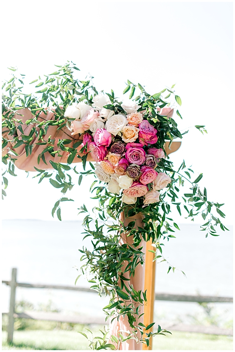 A rustic ceremony arch laced with white and blush pink roses and hints of greenery