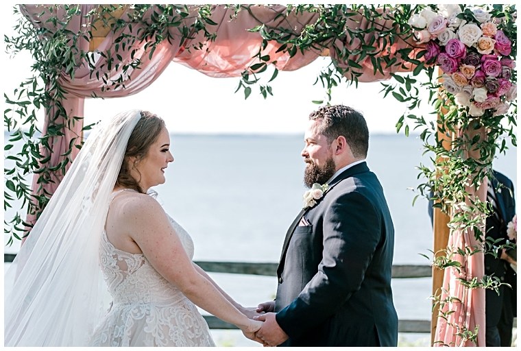 The newlyweds stand hand in hand at their waterfront ceremony at Great Oak Manor. | My Eastern Shore Wedding