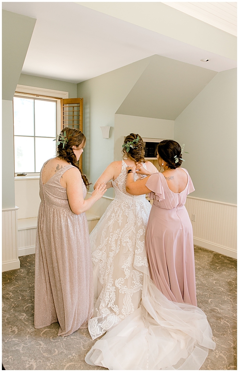 Bridesmaids help the bride into her lace wedding gown in the bridal suite at Great Oak Manor. | Erin Wheeler Photography
