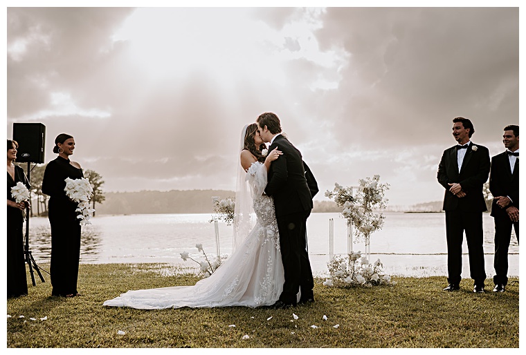 The newlyweds share in a romantic first kiss as husband and wife on the waterfront at Kingsbay Mansion  | My Eastern Shore Wedding