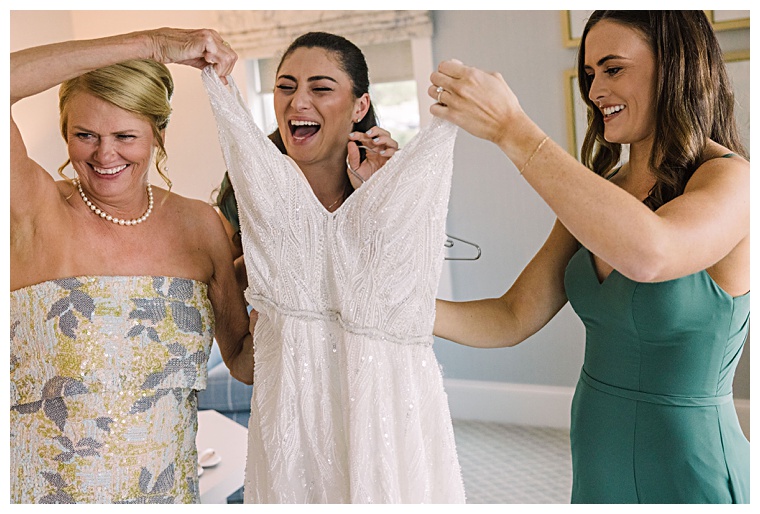 Exuding excitement, the bridesmaids help the bride into her gown | Laura's Focus Photography | My Eastern Shore Wedding