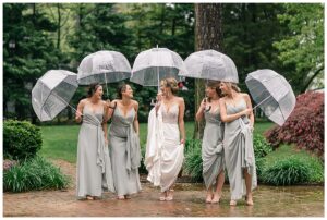 Surrounded by her bridesmaids the soon to be wife takes a stroll through the garden in the sprinkling rain
