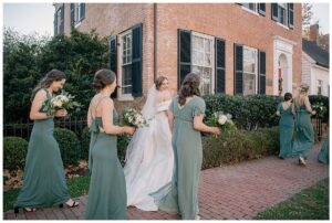 Dressed in sage green gowns, the bridesmaids surround the bride on her way to meet the groom