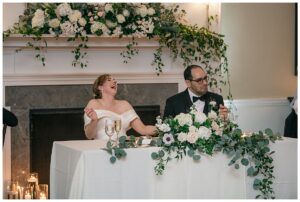 The bride and groom listen to toasts in their honor as they sit at their private sweetheart table