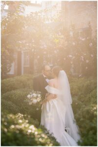 A hazy portrait of the bride and groom during their first look is framed by golden hour sunrays