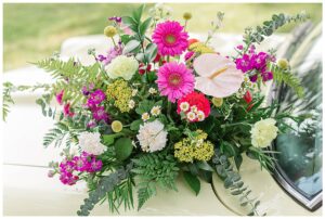A beautiful and bright floral arrangement by Three Little Buds with hot pinks and bold reds and greens
