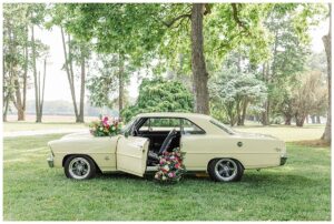 A classic vintage car decorated with bright and vibrant flowers by Three Little Buds