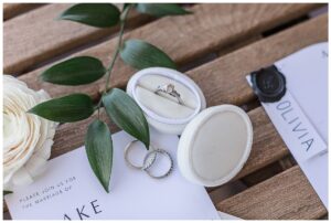 A detail shot of the wedding rings with soft greenery by Three Little Buds