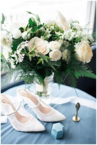 A detail image of the bridal bouquet with the ring box and wedding shoes