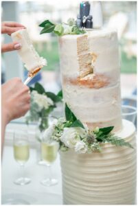 A two tiered wedding cake by Millstream Farm Bakeshop is cut by the new husband and wife to share with their family and friends.