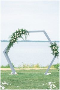 A hexagonal archway is decorated with garland of greenery and white roses by Sherwood Florist