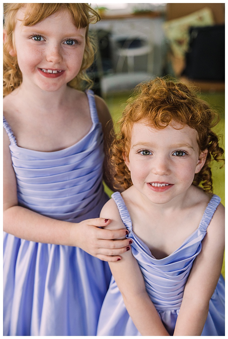 The flower girls pose for a portrait dressed in pastel purple and lavender colored dresses