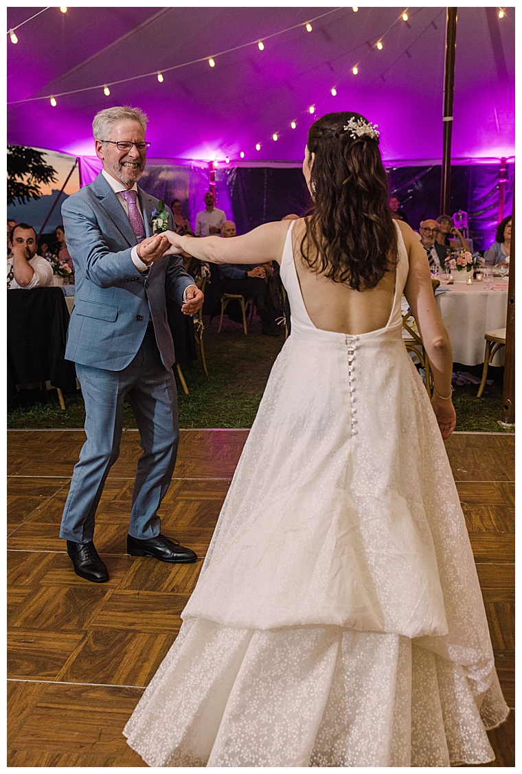The bride enjoys a dance with her father with her lace dress bustled in pearls