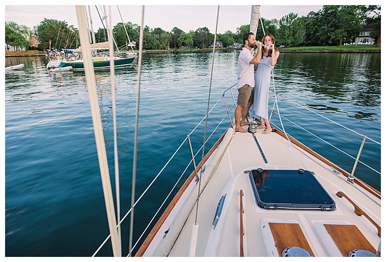 This newly engaged couple shares a toast on the bow of a stunning sailboat at the Chesapeake Bay Maritime Museum