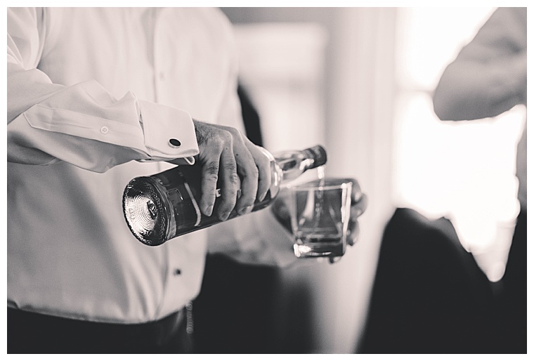 The groom pours shots of whiskey for his groomsmen as they get ready for the ceremony