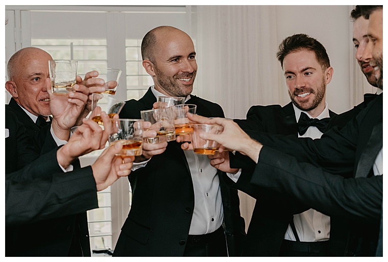 A toast to the bride and groom with shots of whiskey in the groom's suite before the men depart for the ceremony