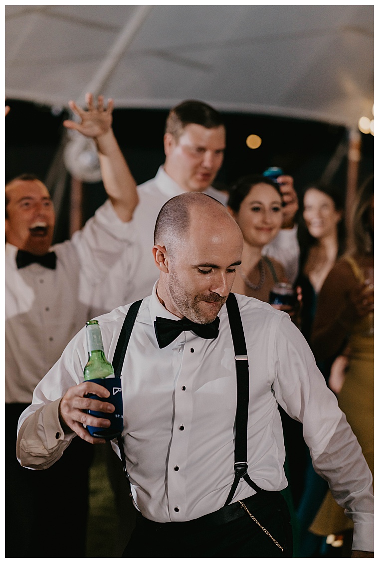 Cheers to the newlyweds, a guest dances on the dance floor with a beverage celebrating the bride and groom