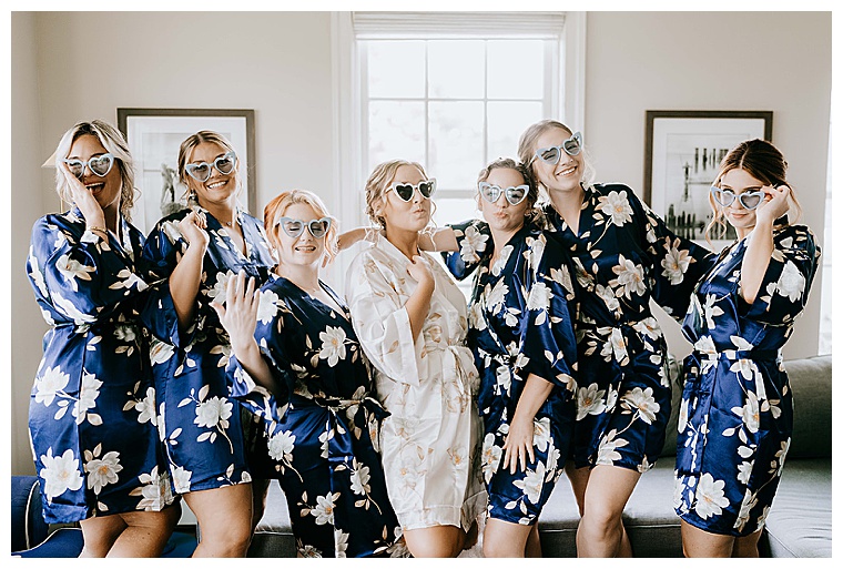 Donned in blue floral robes, the bridesmaids surround the bride in a set of matching heart sunglasses as they get ready for the big day