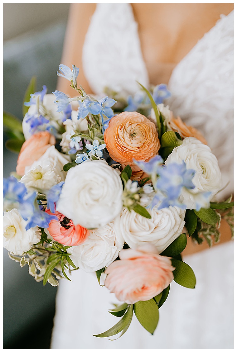 The brides bouquet is completed of stunning white and dusty peach roses with pops of blue and greenery throughout