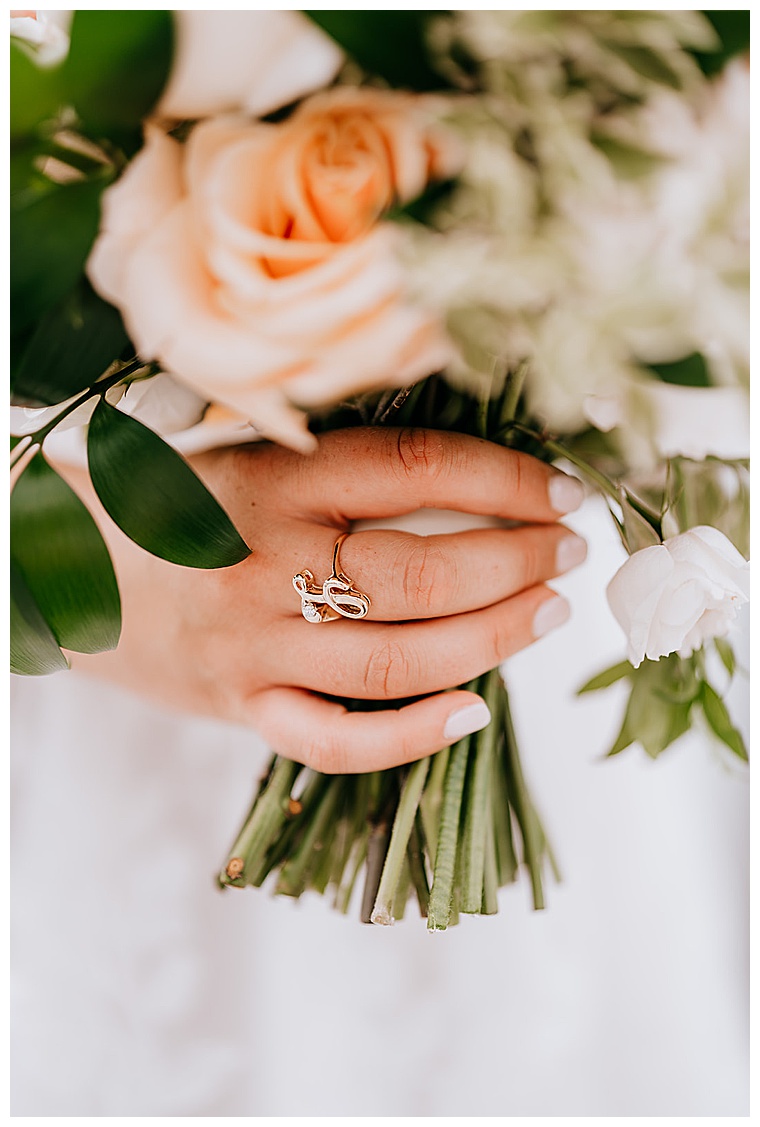 The bride holds her bouquet for a detail portrait image of her ring and roses