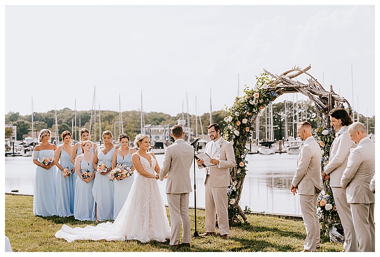 The bride and groom exchange their wedding vows under a romantic and mystical driftwood archway on the waterfront at the Inn at Haven Harbour
