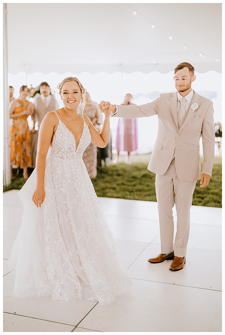 Dressed in a stunning a-line bridal gown with lace details and an american bustle the bride joins her new husband on the dance floor fo their first dance