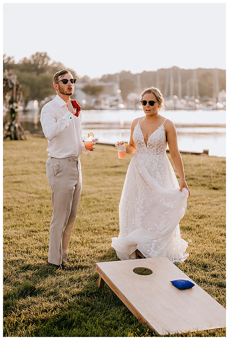The newlyweds participate in a game of cornhole on the waterfront lawn at the Inn at Haven Harbour