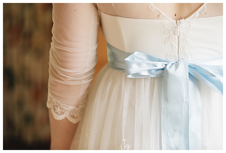 This bride has something blue built into her dress with a dusty blue ribbon belt