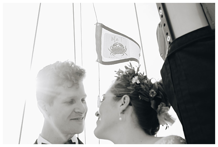 A beautiful black and white portrait of the bride and groom with their custom wedding flag sailing high in the wind on the Tred Avon River