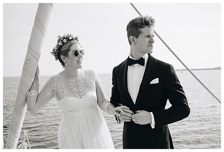 A black and white wedding portrait of the bride and groom sailing on the tred avon river dressed in a classic black tux and a gorgeous lace wedding gown