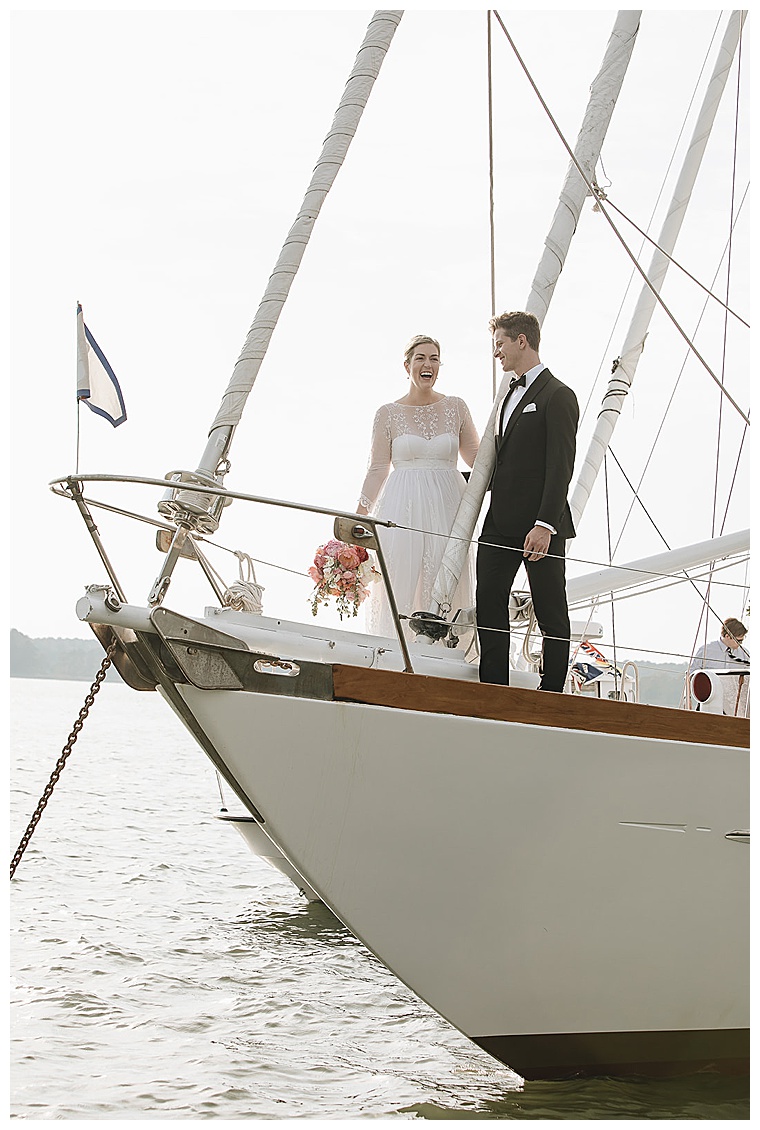 The bride and groom look snappy on the bow of their ceremony sailboat anchored in the tred avon river for a fabulous oxford md wedding